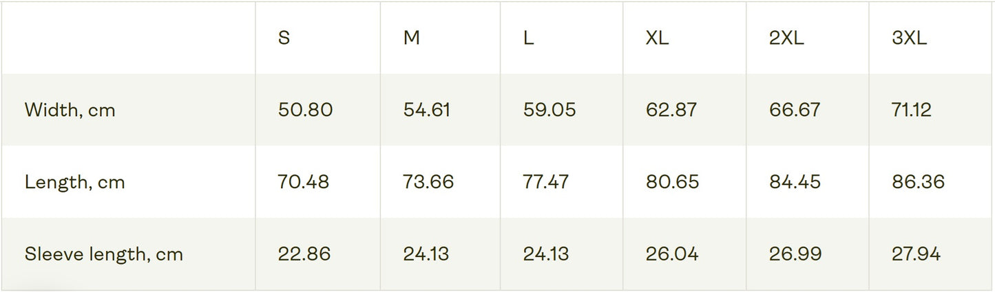 Size chart of the unisex heavy carded cotton T-shirt with a boxy fit, featuring a woman who sits in front of a softly lit vanity mirror, framed by diagonal tones of pine and sea green. Her expression is poised and calm, capturing quiet confidence without performance. From ModeK Vetements.