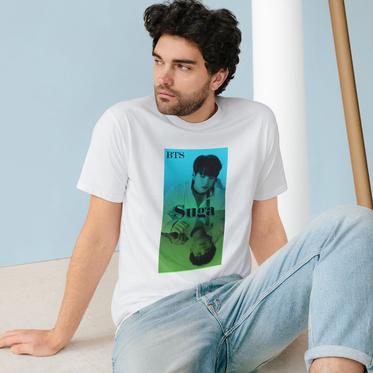 Man wearing a unisex combed organic cotton T-shirt in white, featuring Agust D (Suga of BTS) in a turquoise-to-green gradient design. His clear image sits above, while a mirrored reflection below is overlaid with horizontal scan lines, suggesting a digital echo or filtered version of the original. From ModeK Vetements.