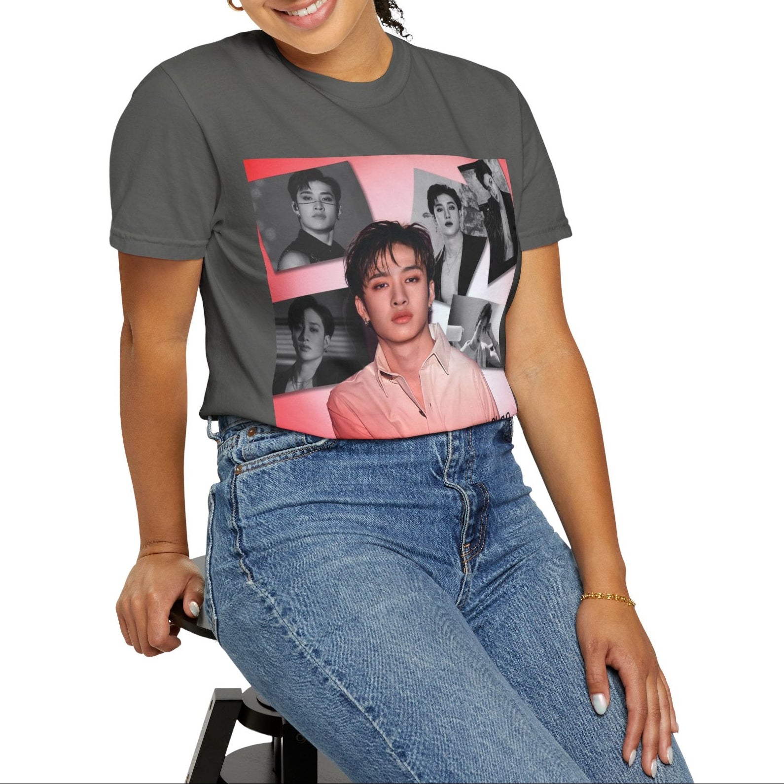 Model sitting on a stool and showcasing the Bang Chan Stray Kids Unisex T-Shirt in pepper, featuring a soft pink glow and black-and-white portraits. A design capturing his warmth, quiet confidence, and magnetic presence. 100% ring-spun cotton from ModeK Vetements.