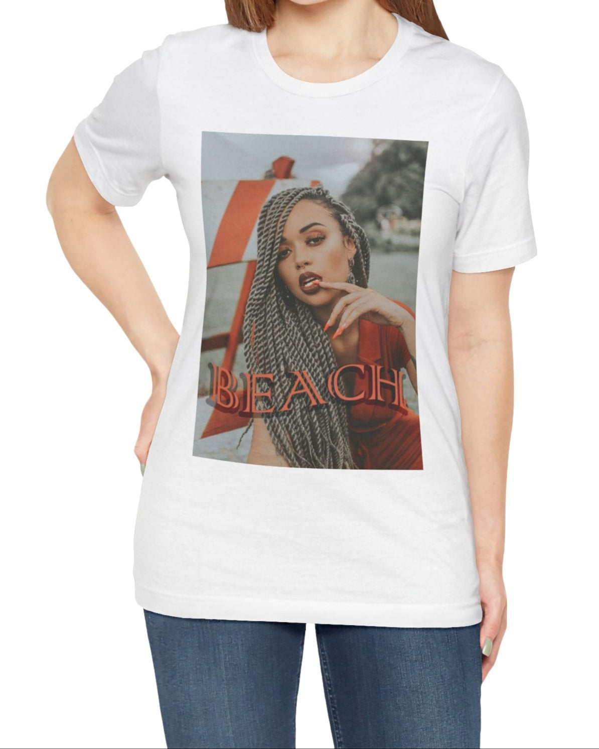 Portrait of a confident woman with long braids posing in front of an orange-and-white no-entry sign, printed on a unisex T-shirt in white, with the word “BEACH” in bold orange lettering. ModeK Vetements.