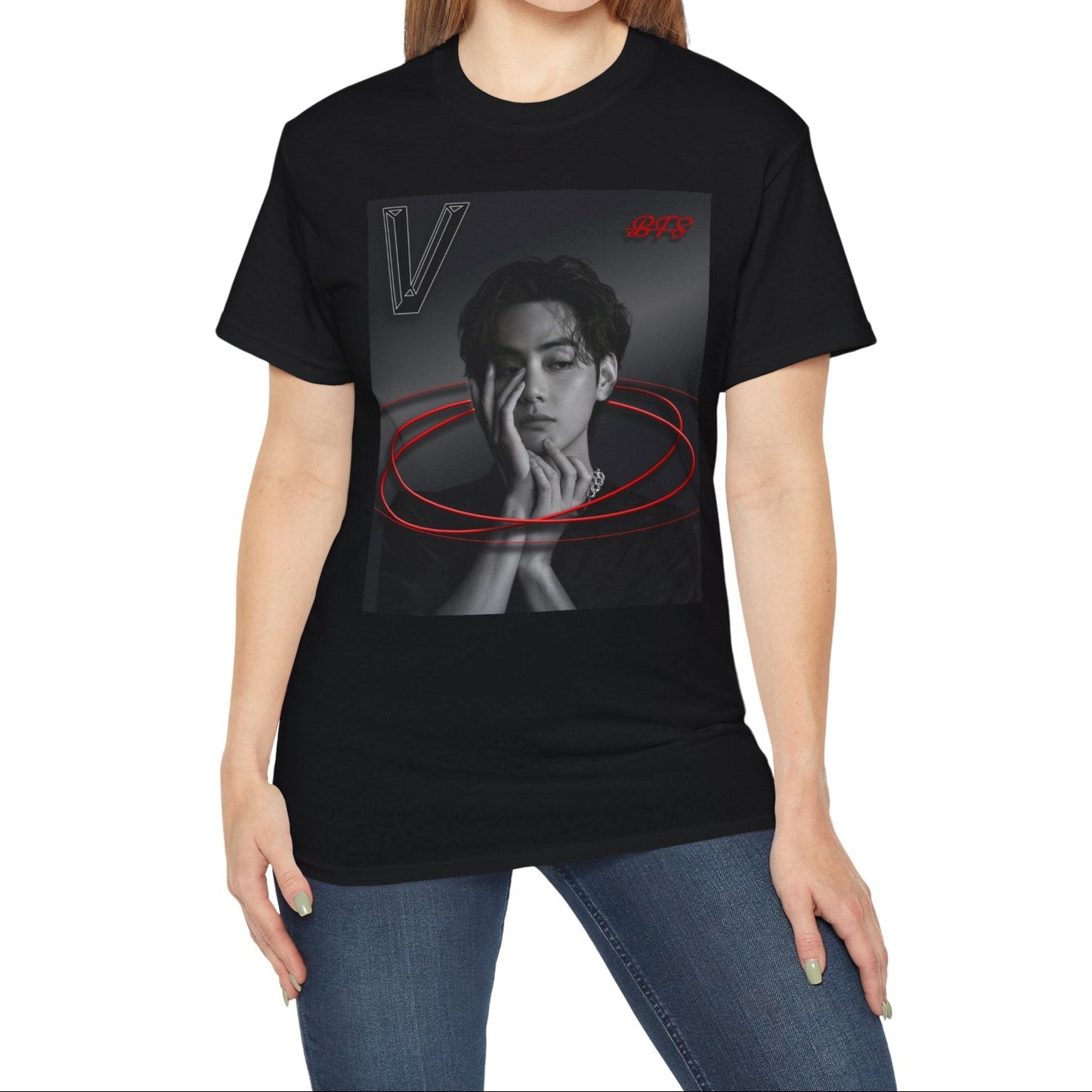 Model showcasing the unisex 100% cotton T-shirt in black. The front of the shirt displays a high-contrast black-and-white portrait of K-pop star V (Kim Taehyung) looking forward with a contemplative expression. Encircling him are vibrant red, glowing 3D oval rings. A styled "V" appears in the top-left corner and a red "BTS" logo in the top-right corner. From ModeK Vetements.