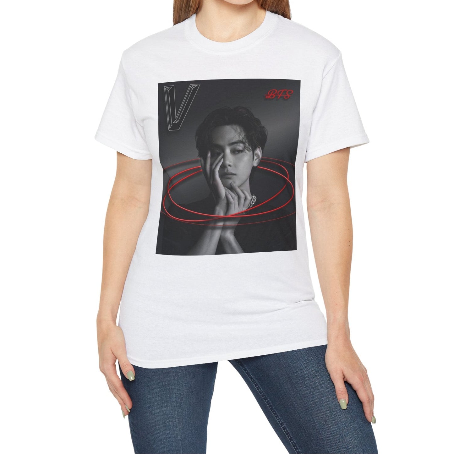 Model showcasing the unisex 100% cotton T-shirt in white. The front of the shirt displays a high-contrast black-and-white portrait of K-pop star V (Kim Taehyung) looking forward with a contemplative expression. Encircling him are vibrant red, glowing 3D oval rings. A styled "V" appears in the top-left corner and a red "BTS" logo in the top-right corner. From ModeK Vetements.