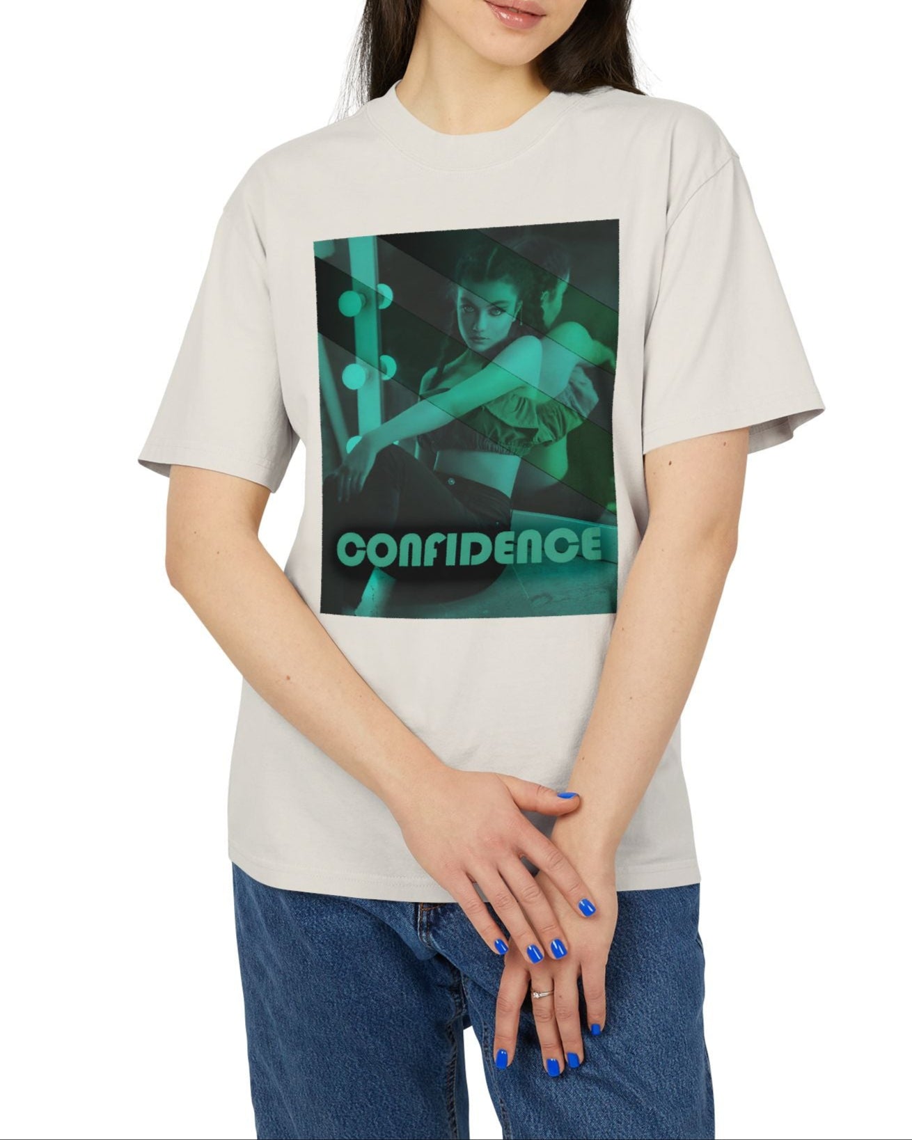 Unisex heavy carded cotton T-shirt in faded bone with a boxy fit, featuring a woman who sits in front of a softly lit vanity mirror, framed by diagonal tones of pine and sea green. Her expression is poised and calm, capturing quiet confidence without performance. From ModeK Vetements.