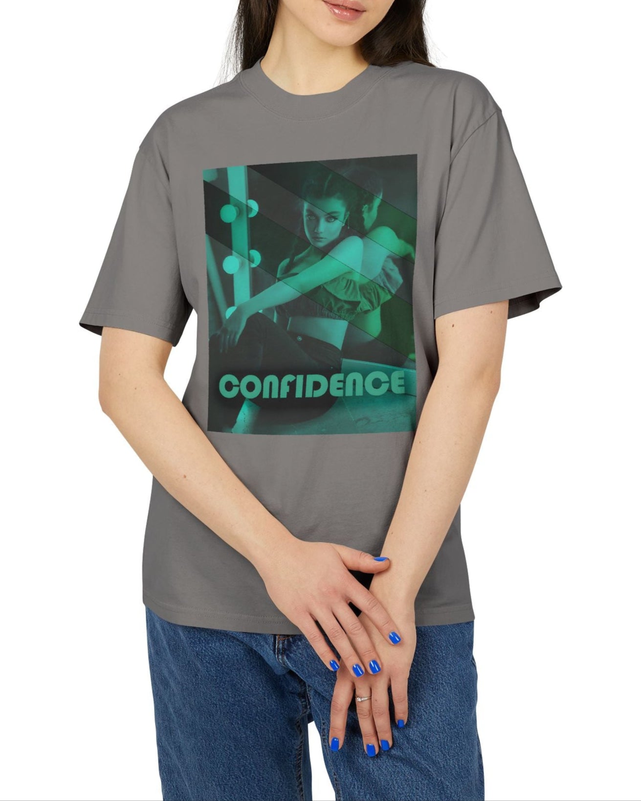 Unisex heavy carded cotton T-shirt in faded grey with a boxy fit, featuring a woman who sits in front of a softly lit vanity mirror, framed by diagonal tones of pine and sea green. Her expression is poised and calm, capturing quiet confidence without performance. From ModeK Vetements.