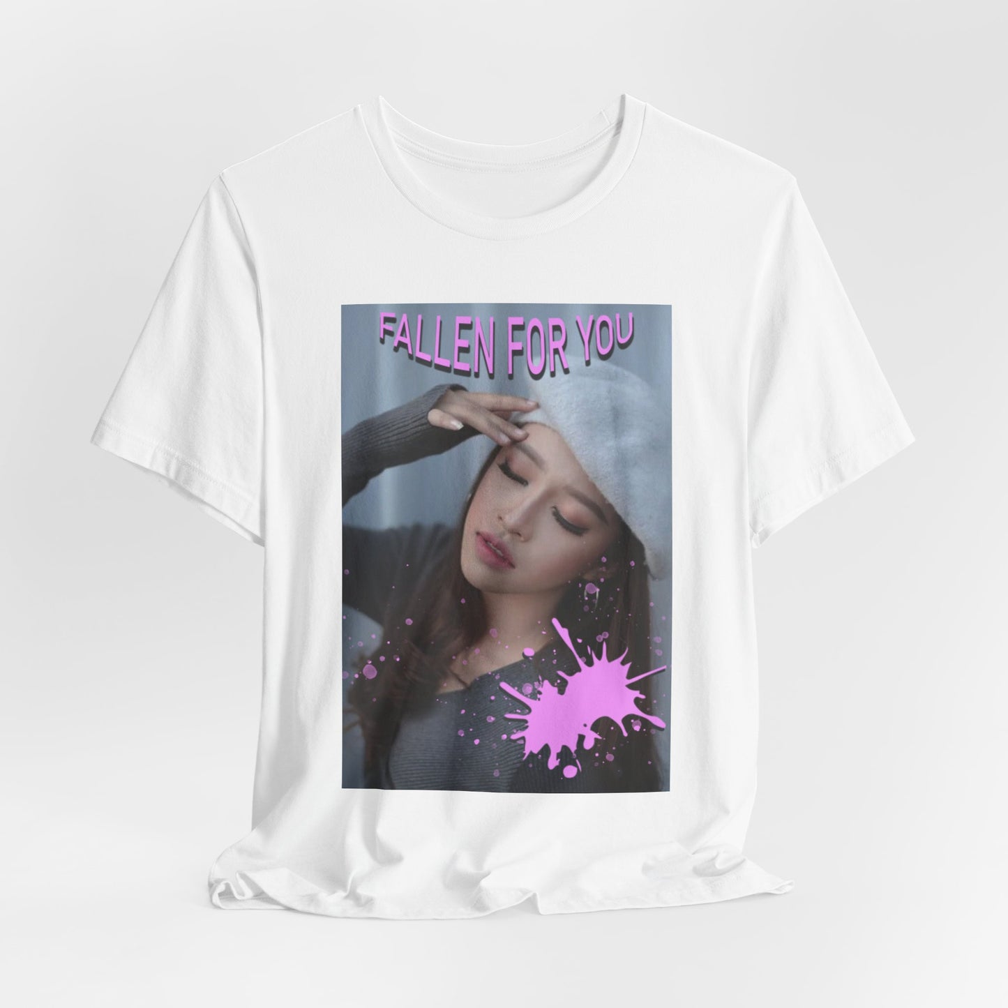 Draped unisex T-shirt in white, featuring a dreamy photo of a woman with closed eyes, a soft expression, and a pink paint splash over her chest. The words “FALLEN FOR YOU” appear in bold pink lettering at the top. ModeK Vetements.