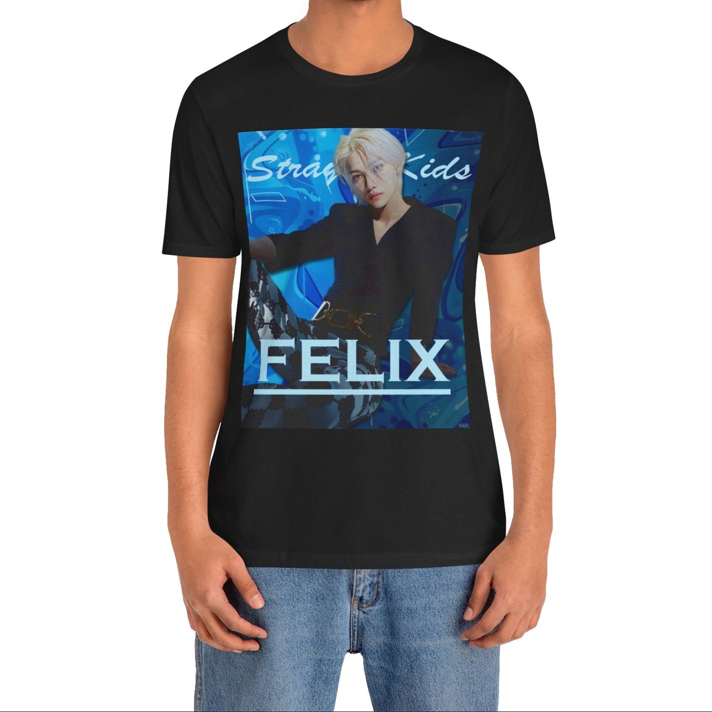 Male model showcasing the unisex, 100% airlume combed & ring-spun cotton t-shirt in black, featuring a graphic design. It shows Felix from Stray Kids in a provocative pose, wearing a structured black suit jacket and oriental-style patterned pants. The background is a multi-toned blue graffiti. From ModeK Vetements.