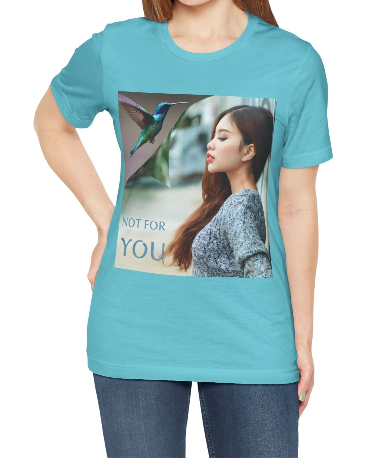 Unisex airlume combed, ring-spun cotton T-shirt in turquoise, featuring a turning-page effect that reveals a hummingbird in flight. Inspired by the lightness, color, and serenity of the bird, the design evokes grace, freedom, and a soul that seeks only the nectar of life. From ModeK Vetements.