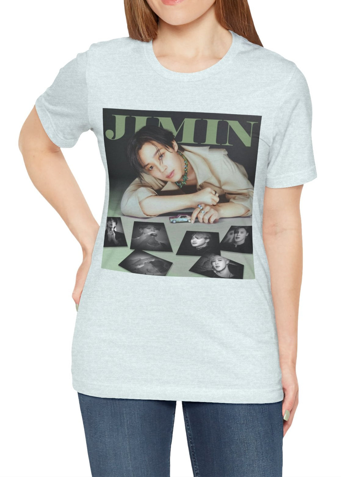 Jimin BTS Unisex T-Shirt in heather ice blue – A Playful Charm. A stylish design featuring Jimin leaning forward while interacting with a miniature car. Soft, muted tones and balanced lighting highlight his delicate features, complemented by black-and-white portrait prints that add an editorial touch. ModeK Vetements.