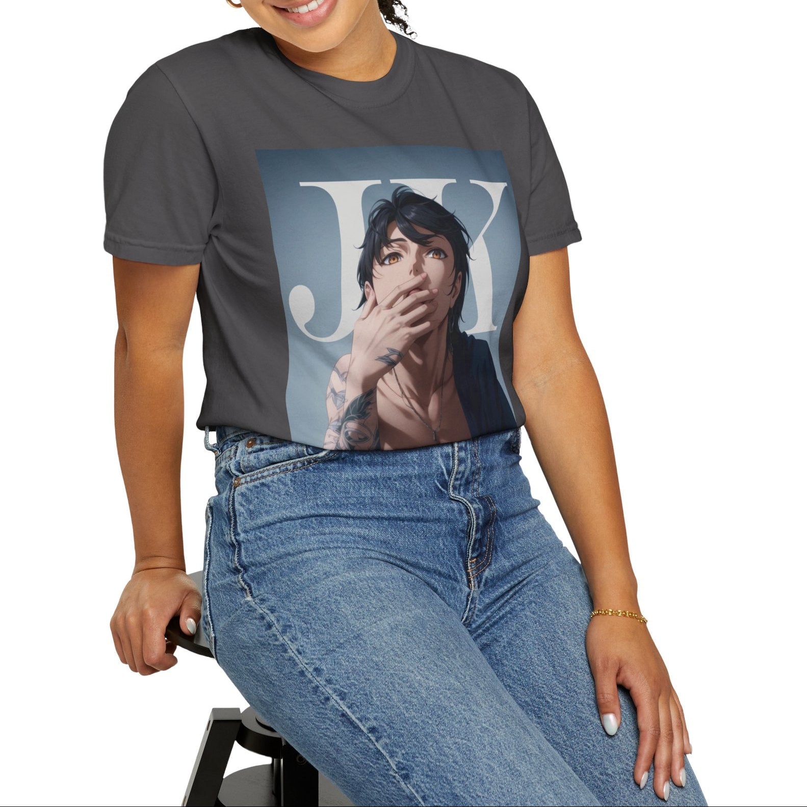 Model sitting on a stool and showcasing the Anime-style unisex T-shirt in graphite, featuring Jungkook, blending K-pop stage presence with anime aesthetics. The design captures his intense gaze, flowing hair, and striking composition, creating a fusion of two beloved art forms. Printed on soft, breathable ring-spun cotton for comfort and style. ModeK Vetements.