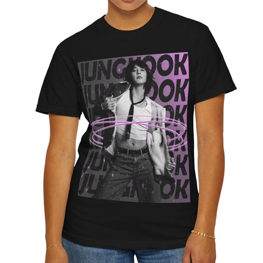 Unisex 100% ring-spun cotton T-Shirt in black, featuring BTS's Jungkook. He is posing against a dark background with "JUNGKOOK" repeated in large black typography and a charcoal-lavender gradient with pink paint splatters. Three glowing, thin magenta hoops encircle his waist, creating a sense of motion, making him even more provocative. From ModeK Vetements.