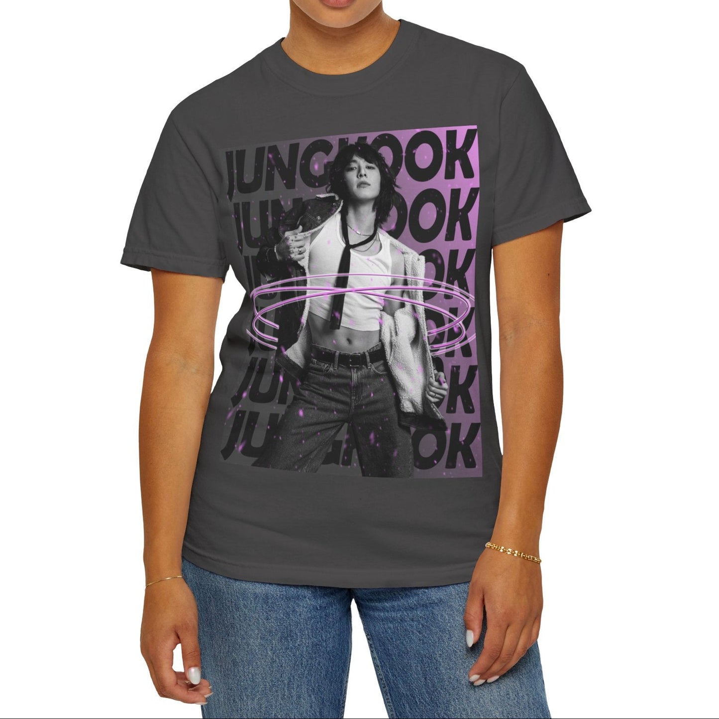 Unisex 100% ring-spun cotton T-Shirt in graphite, featuring BTS's Jungkook. He is posing against a dark background with "JUNGKOOK" repeated in large black typography and a charcoal-lavender gradient with pink paint splatters. Three glowing, thin magenta hoops encircle his waist, creating a sense of motion, making him even more provocative. From ModeK Vetements.