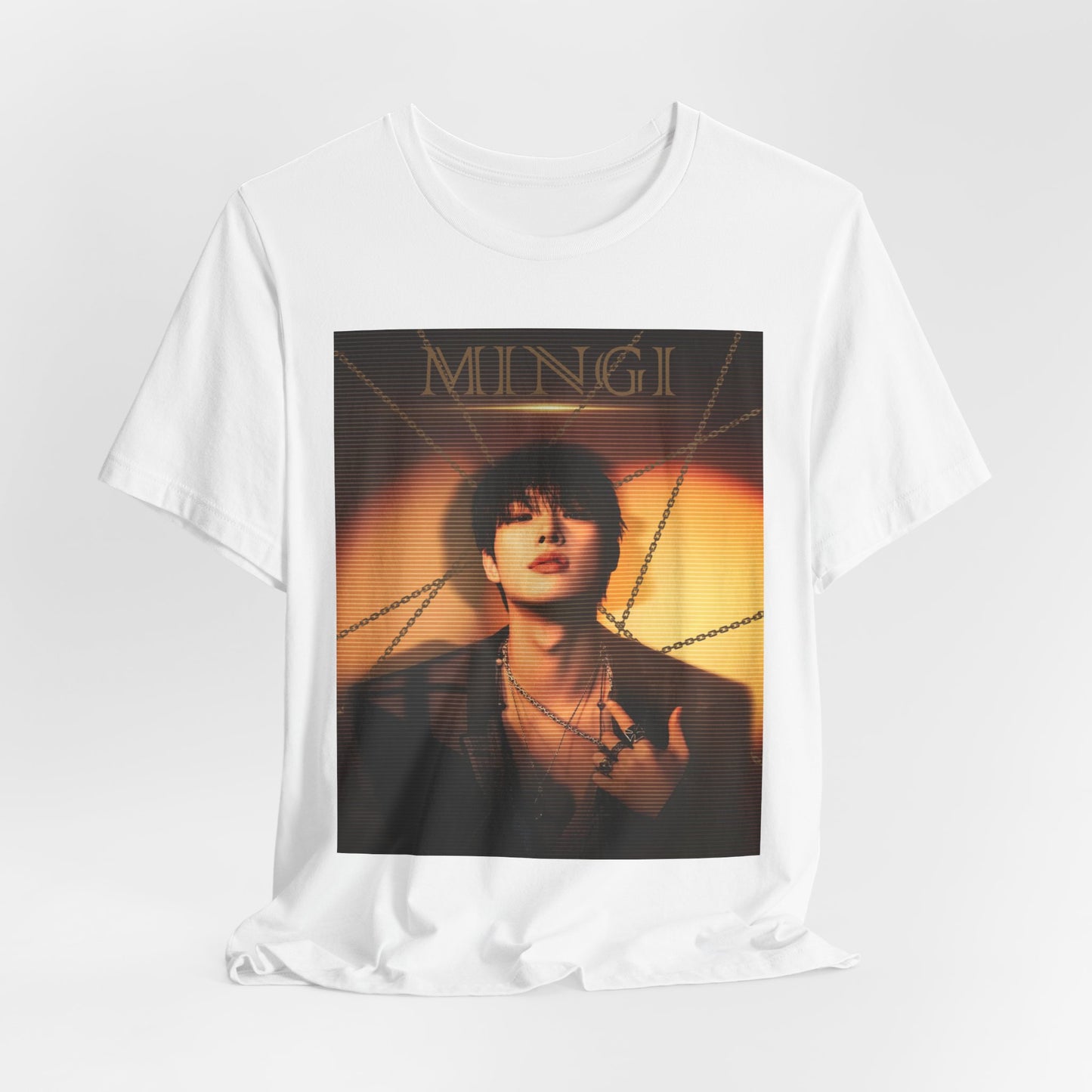 Mingi ATEEZ unisex T-shirt in white, draped naturally to highlight the soft fabric and relaxed fit. The design features a golden-hour portrait with a scan line effect, layered chains, and bold typography, creating a dramatic and elegant aesthetic. Made from 100% Airlume cotton for a breathable and lightweight feel. From ModeKVetements.