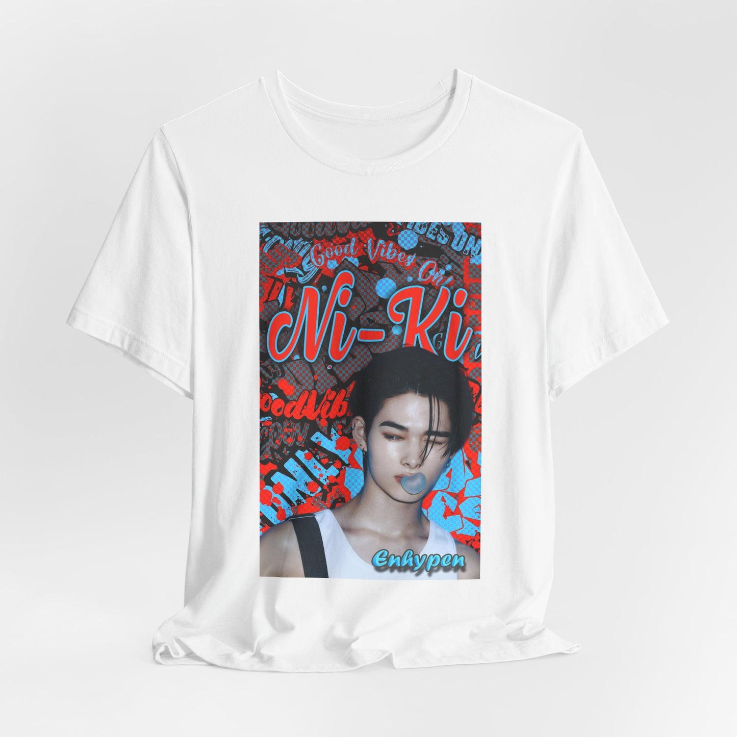 Draped Unisex airlume cotton T-shirt in white, featuring Ni-Ki of ENHYPEN layered into a bold graffiti-style design with Rosso Corsa red and Malibu Blue. The layout includes digital splashes, checkerboard effects, and a bubble gum moment frozen mid-pop. From ModeK Vetements.