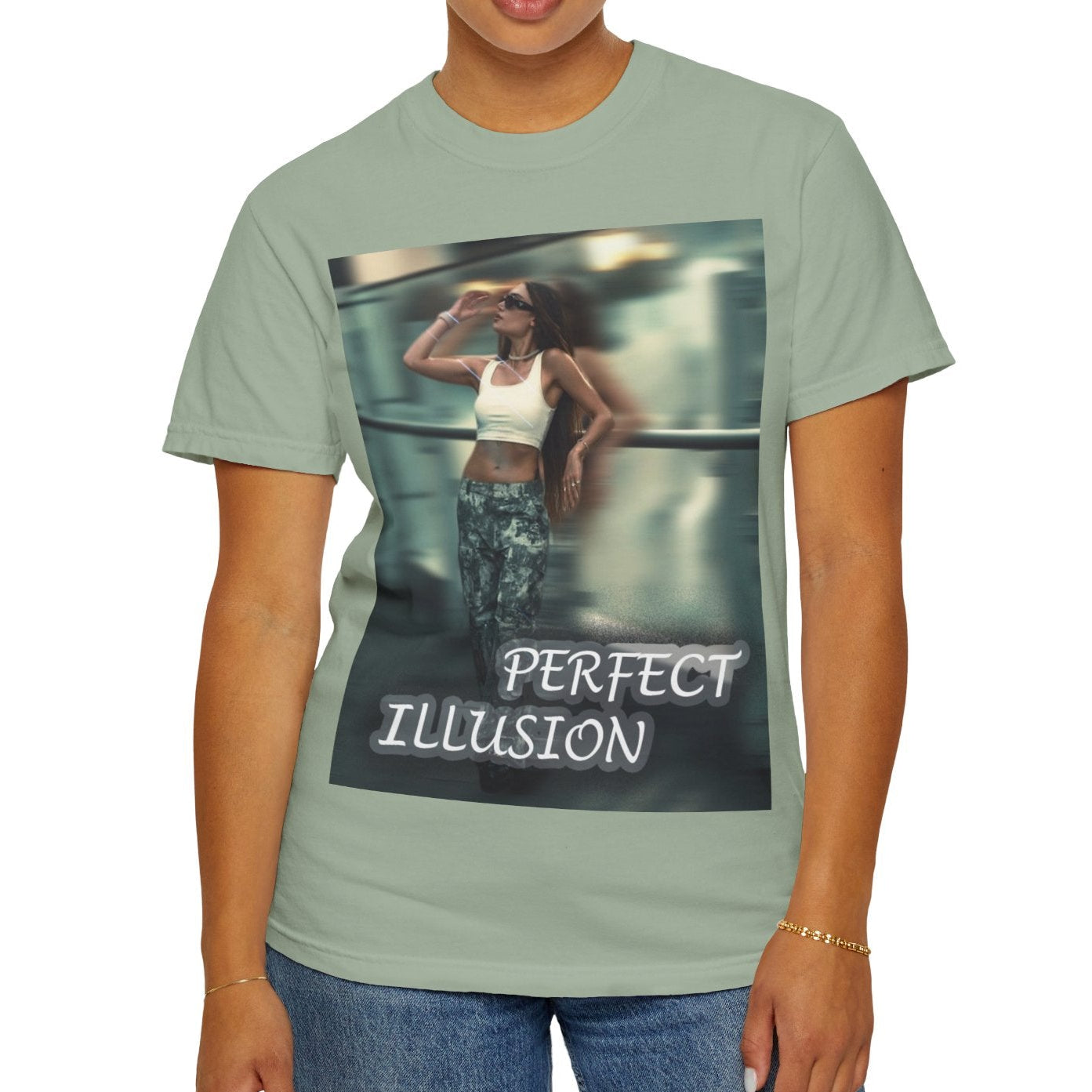 Unisex 100% ring-spun cotton t-shirt in bay, featuring a graphic design, where a woman in tactical camo cargo pants and a white crop top stands as a sharp anchor against a blurry, cinematic urban background. The design also features a digital dispersion effect and electric blue rays, symbolizing the "Perfect Illusion" where brute force hides a deeper reality of tenderness and beauty. From ModeK Vetements.