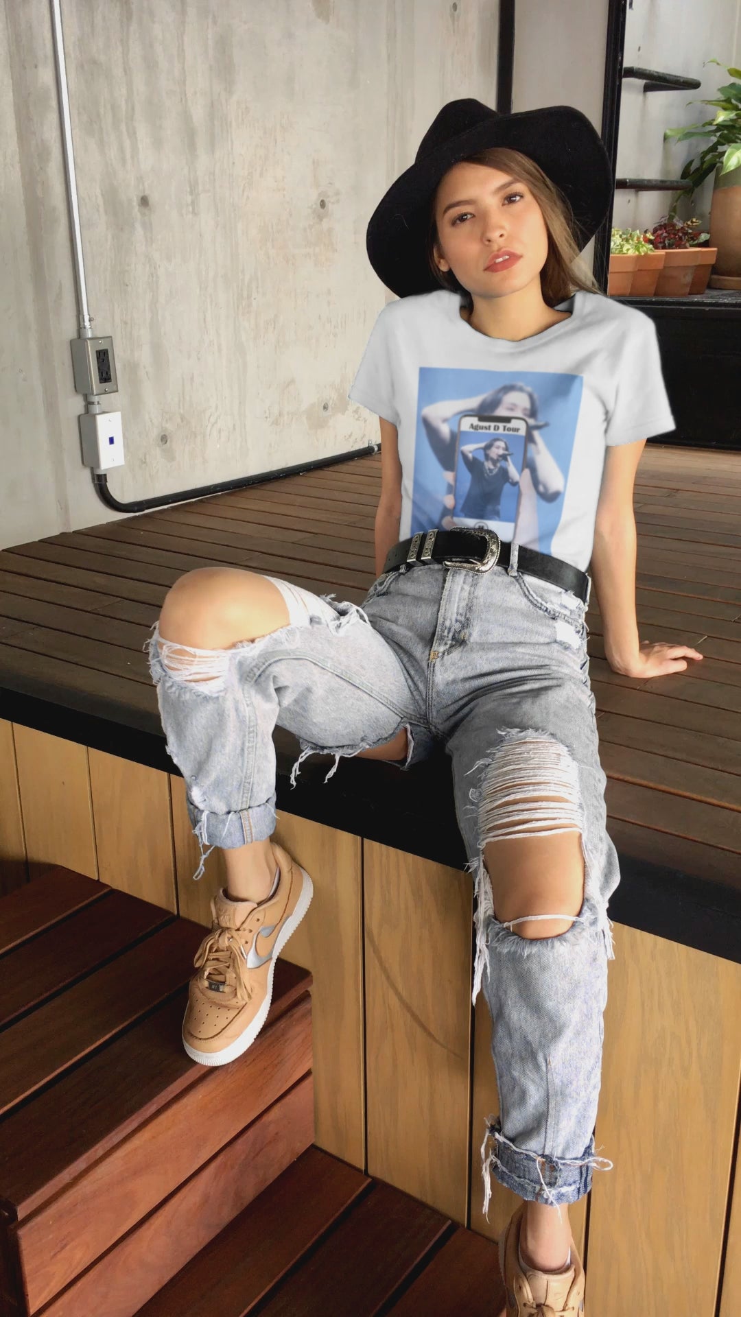 Video showcasing the Unisex T-shirt in white, featuring BTS’s SUGA mid-performance during the Agust D Tour, shown through a phone screen with a video player overlay. The foreground is sharp and vivid, while the background is softly blurred. ModeK Vetements. 