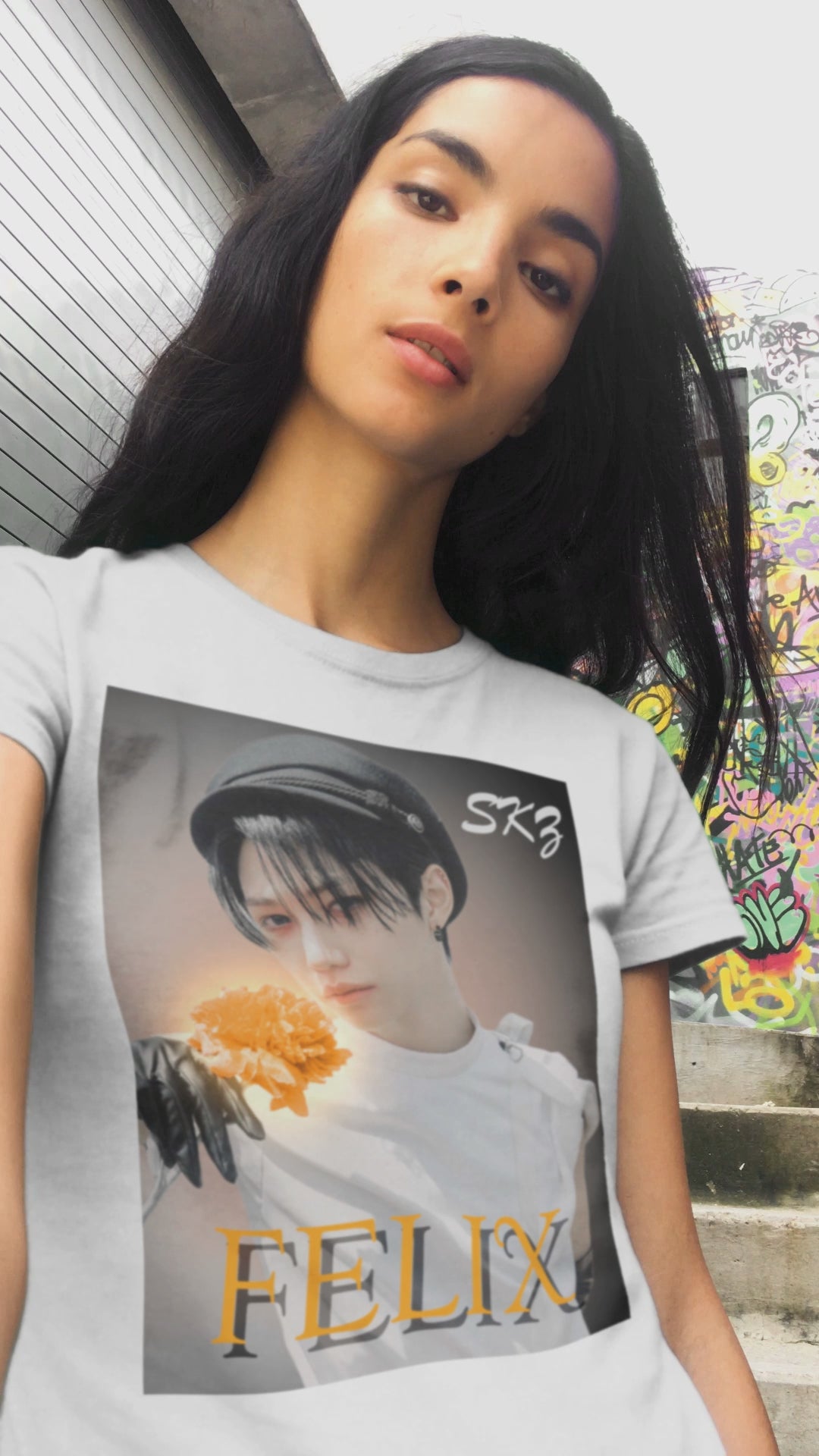 Video showcasing the Felix Stray Kids unisex T-shirt in white, inspired by the 143 MV. Features Felix in white costume with glowing orange flower, contrasted against a dark, cinematic background. ModeK Vetements.