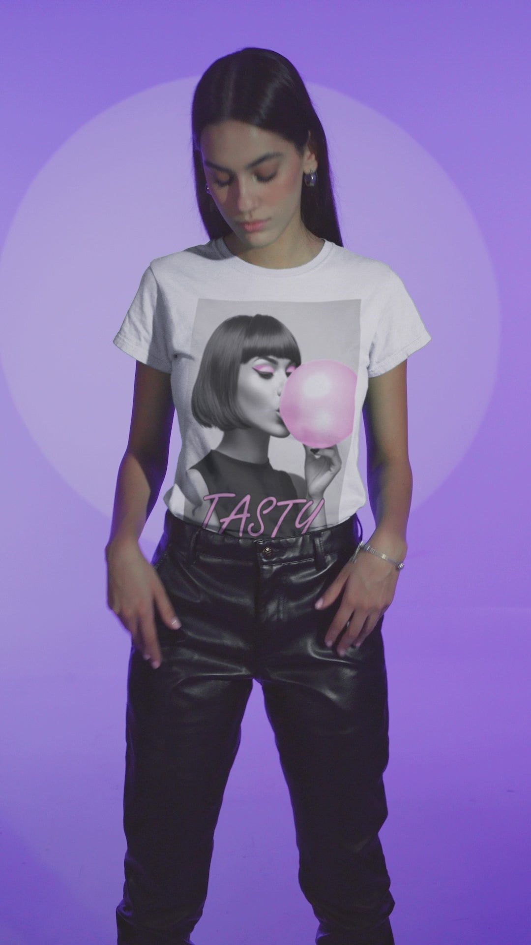 Video showcasing the stylized black-and-white portrait of a woman with a bob haircut blowing a bright pink bubblegum bubble, printed on a T-shirt in white, with the word “TASTY” in pink script. ModeK Vetements.