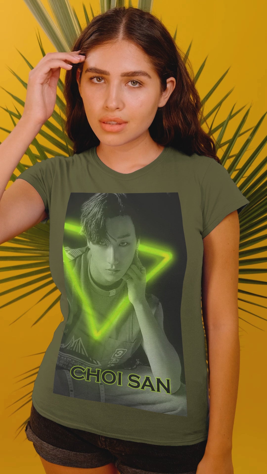 Video showcasing the Choi San ATEEZ unisex cotton t-shirt in military green, featuring a black-and-white portrait with a neon-inspired green triangle behind him. His hand touches the glowing edge. Printed on 100% US cotton, ethically made and Oeko-Tex certified. ModeK Vetements.