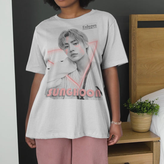 Video showcasing the Unisex oversized heavy cotton T-shirt in white, featuring Sunghoon of ENHYPEN in a synthwave-inspired design with cornflower lilac neon triangle, geometrical face tattoos, and vintage font. From ModeK Vetements.