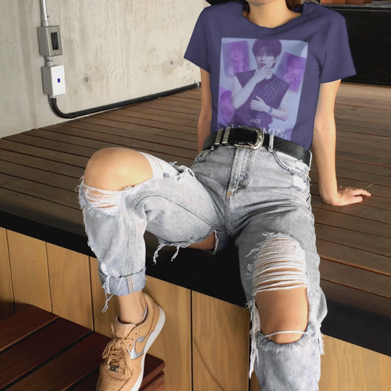 Video showcasing the unisex, jersey, airlume combed and ringspun cotton T-Shirt in team navy, with a graphic design. It features Stray Kids' Seungmin in a sleeveless crochet top and blueberry tie. He poses thoughtfully against a periwinkle backdrop with a mist-covered collage of lavender, magazine-style photos. At the bottom, "SKZ SEUNGMIN" is written in pale lily-blue with a soft drop shadow. From ModeK Vetments.