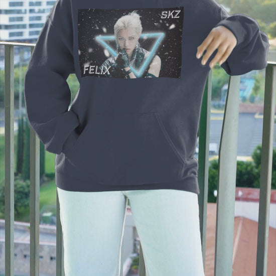 Video showcasing the Unisex cotton-poly blend hoodie in navy, featuring a visual print of Felix from Stray Kids, framed by a glowing blue neon triangle amid falling snow on a dark background. From ModeK Vetements.