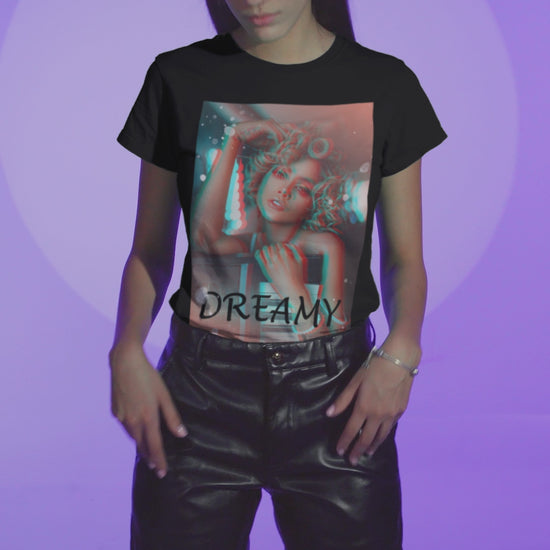Video showcasing the Unisex 100% ring-spun cotton T-Shirt in black featuring a DTG graphic design: a stylized anaglyph portrait of a woman with curly hair, leaning on an electronic keyboard. The design uses a 3D glitch effect with shifting layers of electric blue and bittersweet red-orange, capturing a "DREAMY" cinematic atmosphere. From ModeK Vetements.