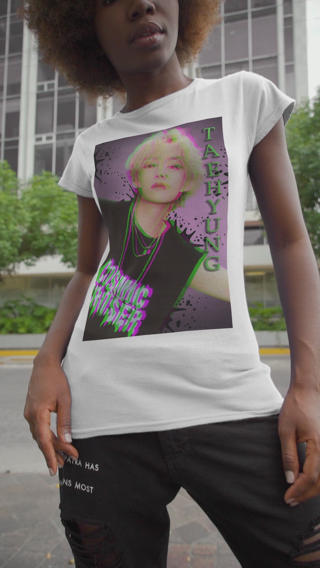 Video showcasing the V Taehyung BTS unisex t-shirt in white, featuring a glitch-effect design in green and magenta with paint splatters, purple gradient background, and Cosmic Cruiser text. Printed on 100% US cotton, ethically made and Oeko-Tex certified. ModeK Vetements.
