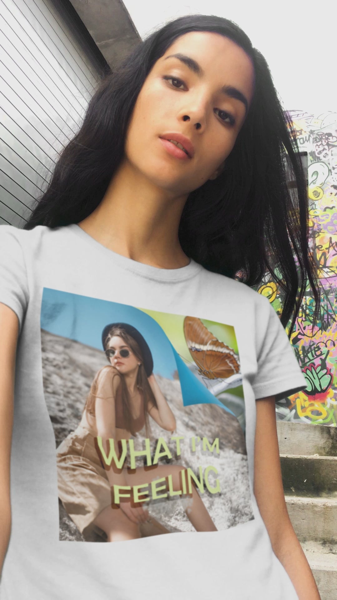 Video showcasing the unisex jersey T-Shirt in white featuring a woman sitting on a sunlit rocky beach with mint text “WHAT I’M FEELING.” A folded corner reveals a rusty-tipped page butterfly. — From ModeK Vetements.