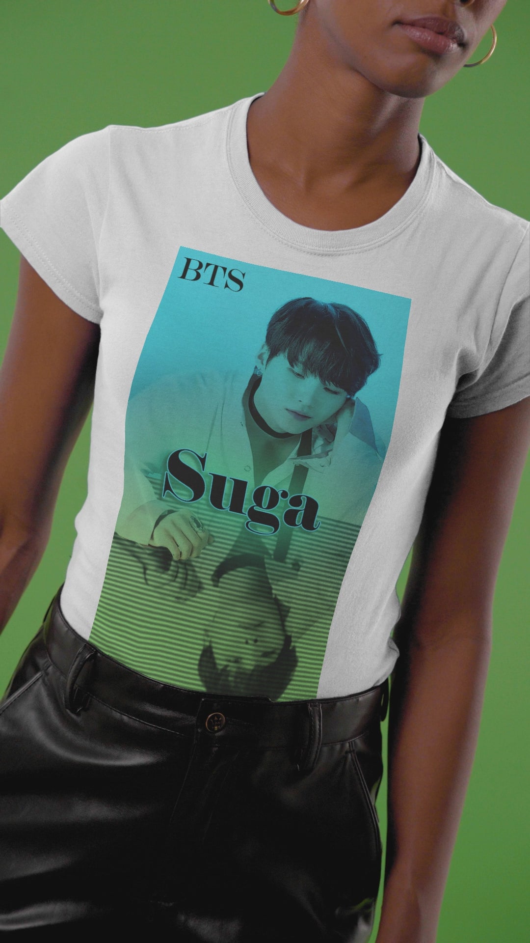 Viideo showcasing the Unisex organic cotton T-shirt featuring Agust D (Suga of BTS) in a turquoise-to-green gradient design. His clear image sits above, while a mirrored reflection below is overlaid with horizontal scan lines, suggesting a digital echo or filtered version of the original. From ModeK Vetements.
