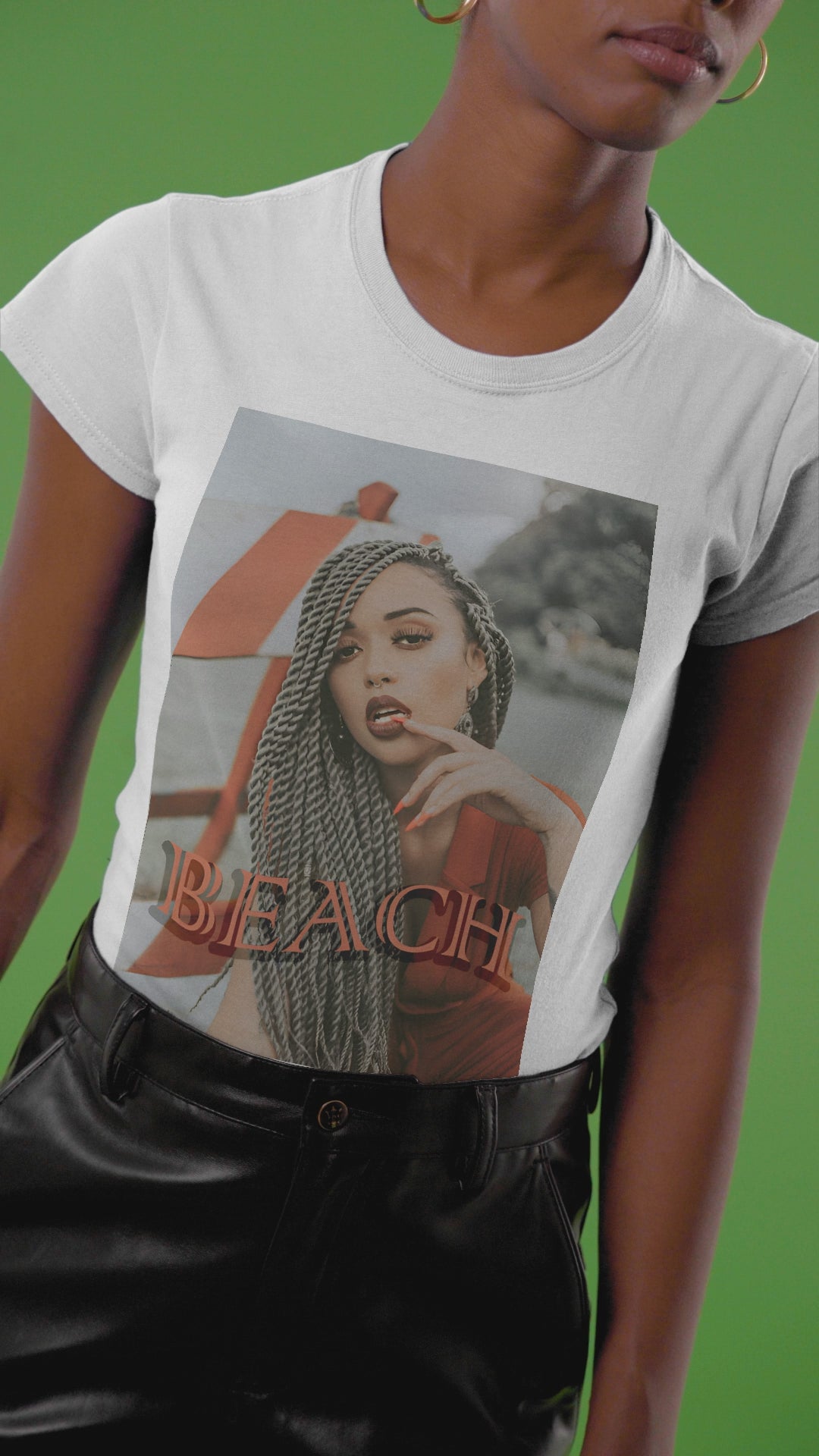 Video showcasing the unisex T-shirt in white featuring a portrait of a confident woman with long braids posing in front of an orange-and-white no-entry sign, with the word “BEACH” in bold orange lettering. ModeK Vetements.