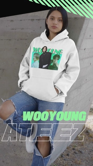 Video showcasing the Unisex hoodie in white, from 100% organic cotton, featuring a photo collage of ATEEZ’s Wooyoung. The central full-body image shows him in a black jacket with a pearl necklace and three safety pins, stepping forward over two bust-level side portraits. Background fades from aquamarine to green-cyan, with bold wintergreen “WOOYOUNG” text above. ModeK Vetements.