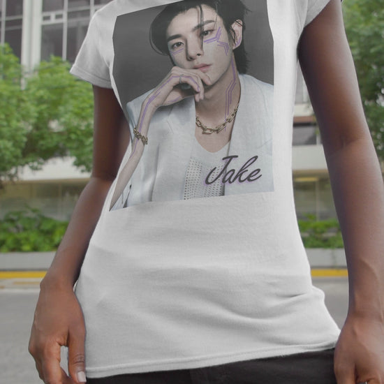 Video showcasing the Unisex airlume cotton T-shirt in white, featuring a print of Jake from ENHYPEN wearing a white jacket with notch lapels and a mesh knit shirt, adorned with bold gold chains and delicate light wisteria circuit-like tattoos emphasizing his cheekbones and jawline. ModeK Vetements.