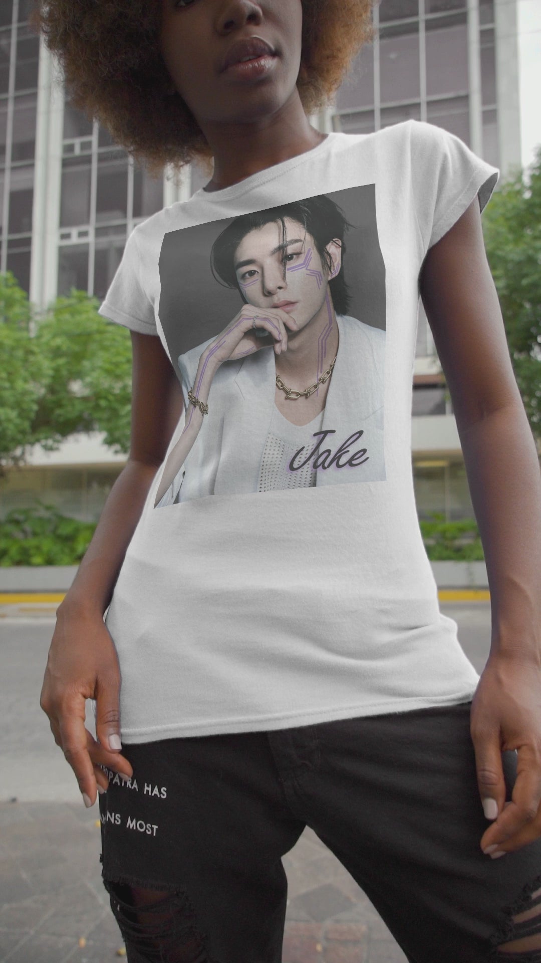 Video showcasing the Unisex airlume cotton T-shirt in white, featuring a print of Jake from ENHYPEN wearing a white jacket with notch lapels and a mesh knit shirt, adorned with bold gold chains and delicate light wisteria circuit-like tattoos emphasizing his cheekbones and jawline. ModeK Vetements.