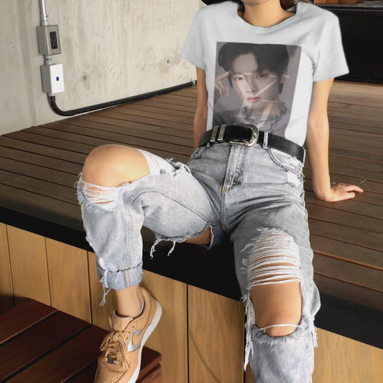 Video showcasing the Yang Jeong-in I.N Stray Kids unisex cotton t-shirt in white, featuring a Y and J layer mask effect that reveals highlights of his face. Includes a silver chain and a gray sweater with brown circular parts made using intarsia knitting. Printed on 100% US cotton, ethically made and Oeko-Tex certified. ModeK Vetements.