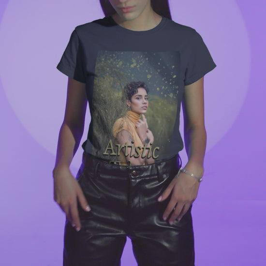 Video showcasing a woman wearing a unisex 100% airlume combed and ring-spun cotton t-shirt in navy featuring a woman in a yellow turtleneck. The image is layered with golden paint splashes creating a sense of motion and "Artistic Talent" where the subject looks real enough to step out of the picture. From ModeK Vetements.