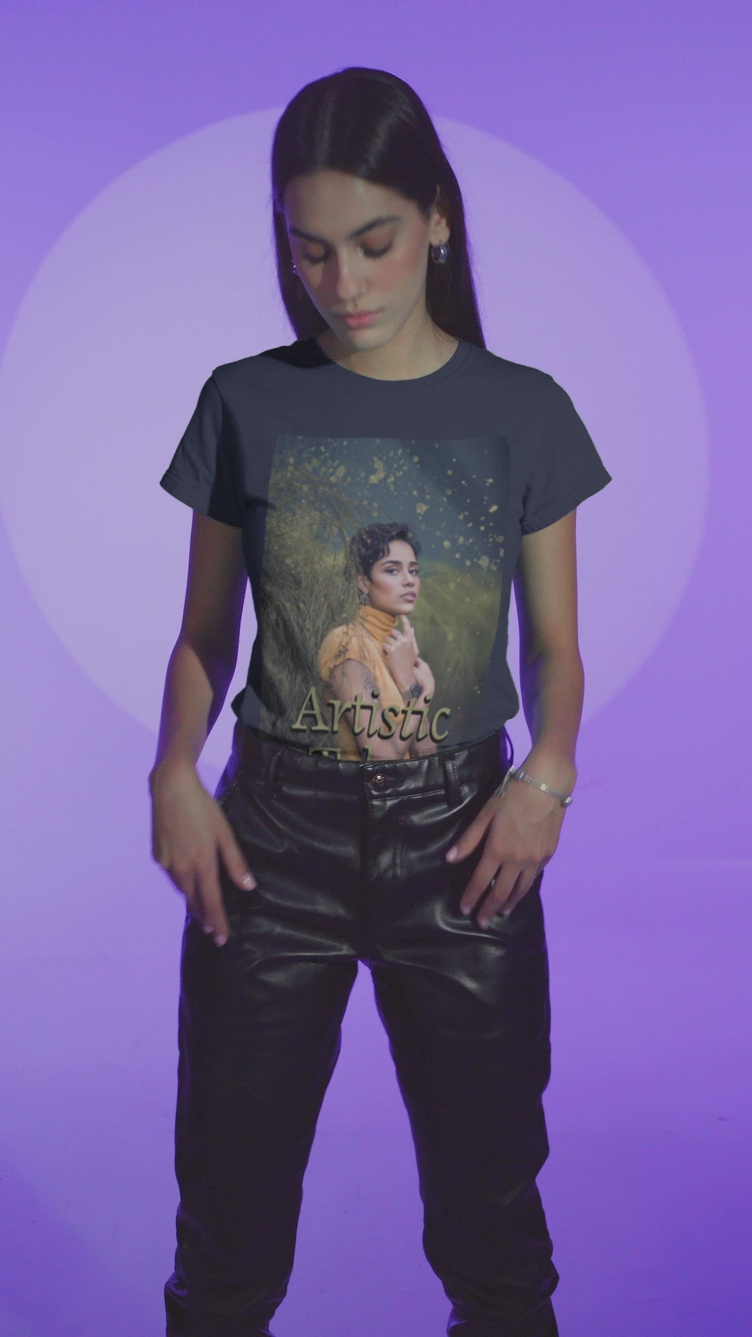 Video showcasing a woman wearing a unisex 100% airlume combed and ring-spun cotton t-shirt in navy featuring a woman in a yellow turtleneck. The image is layered with golden paint splashes creating a sense of motion and "Artistic Talent" where the subject looks real enough to step out of the picture. From ModeK Vetements.
