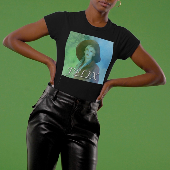 Video showcasing the unisex 100% ring-spun cotton T-Shirt in black, featuring a portrait of Stray Kids' Felix wearing a large hat. It is as if he was painted on canvas with the effect of a mist, blending soft light blue and light green tones. From ModeK Vetements.