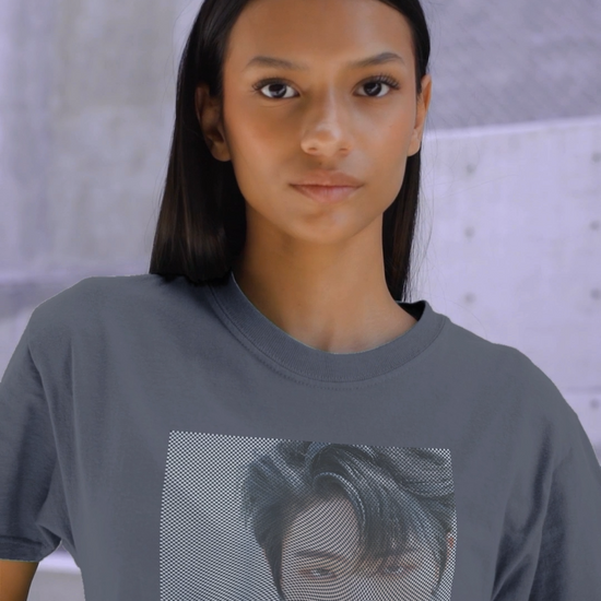 Video showcasing the unisex boxy T-Shirt in faded indigo, featuring a high-contrast graphic portrait of Mingi from the group ATEEZ, overlaid with a dense, wavy halftone moiré pattern. A fine black-and-white grid structure ripples across the image, distorting Mingi’s dark attire to create a powerful three-dimensional optical illusion of digital interference and textured depth. 100% carded cotton from ModeK Vetements.