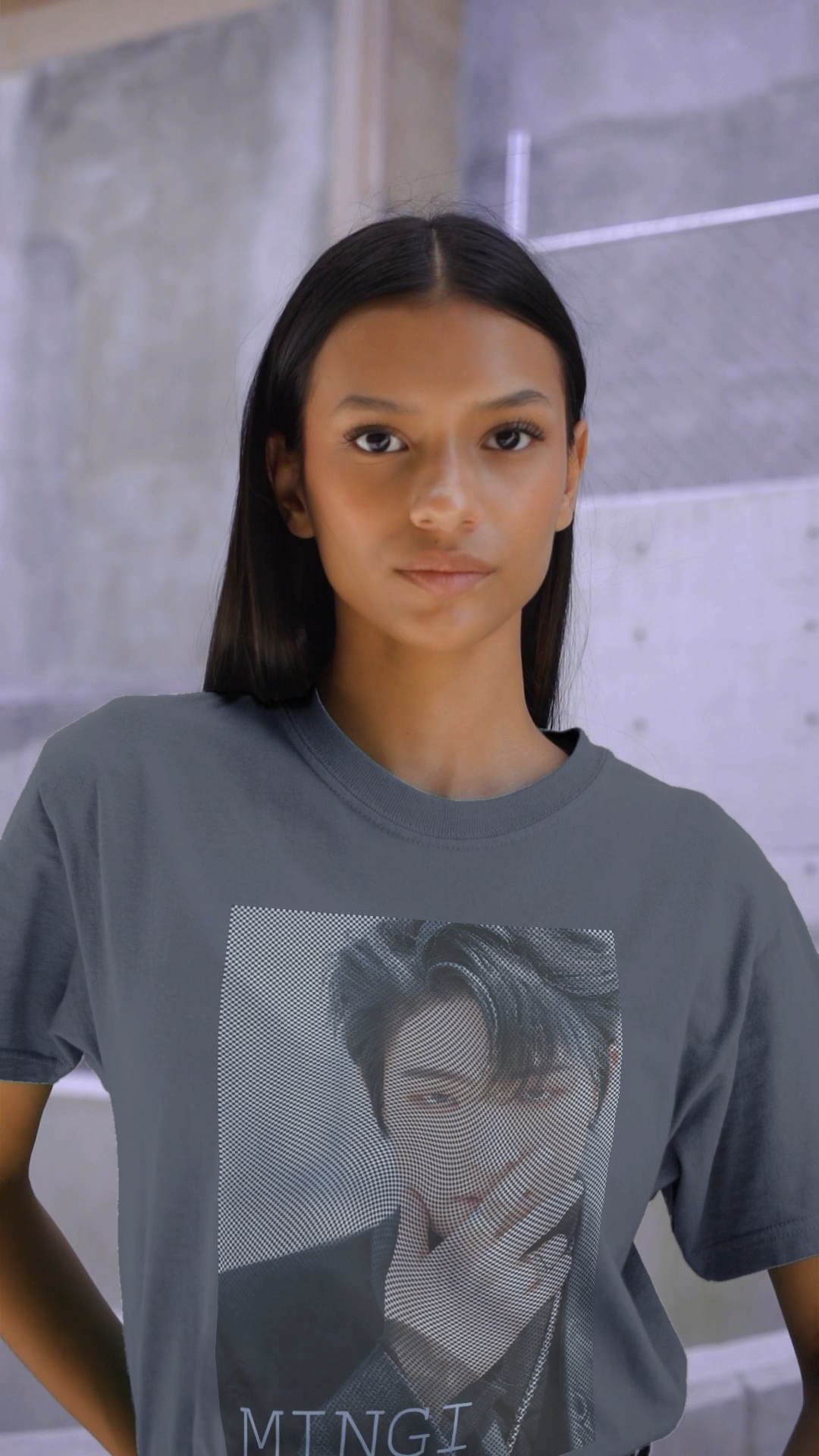 Video showcasing the unisex boxy T-Shirt in faded indigo, featuring a high-contrast graphic portrait of Mingi from the group ATEEZ, overlaid with a dense, wavy halftone moiré pattern. A fine black-and-white grid structure ripples across the image, distorting Mingi’s dark attire to create a powerful three-dimensional optical illusion of digital interference and textured depth. 100% carded cotton from ModeK Vetements.