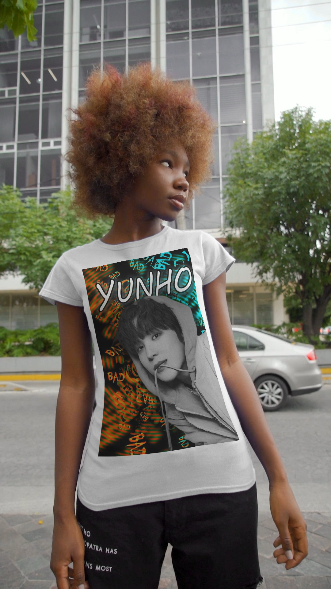 Video showcasing the Unisex airlume combed & ring-spun cotton t-shirt in white, featuring Yunho of ATEEZ in monochrome, biting a drawcord, as glitchy concentric ripples pulse around him. Ferrari red melts into aqua and green — a tempest of color and emotion, suspended mid-thought. From ModeKVetements.