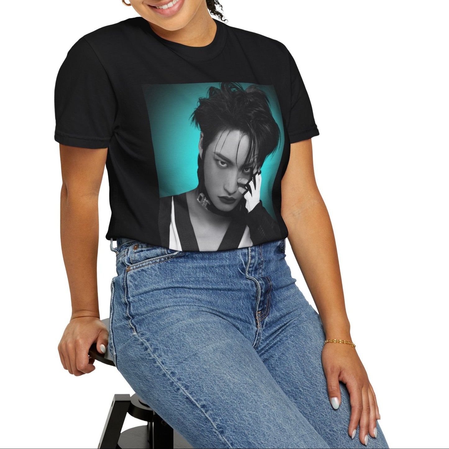 Model sitting on a chair and showcasing the Seonghwa ATEEZ Unisex T-Shirt in black – Experiment in Contrasts. A striking black-and-white portrait of Seonghwa with dramatic lighting, deep shadows, and a piercing gaze. His darkened lips add an intense edge, while a bold teal glow surrounds him, creating a contrast between elegance and raw energy. ModeK Vetements.