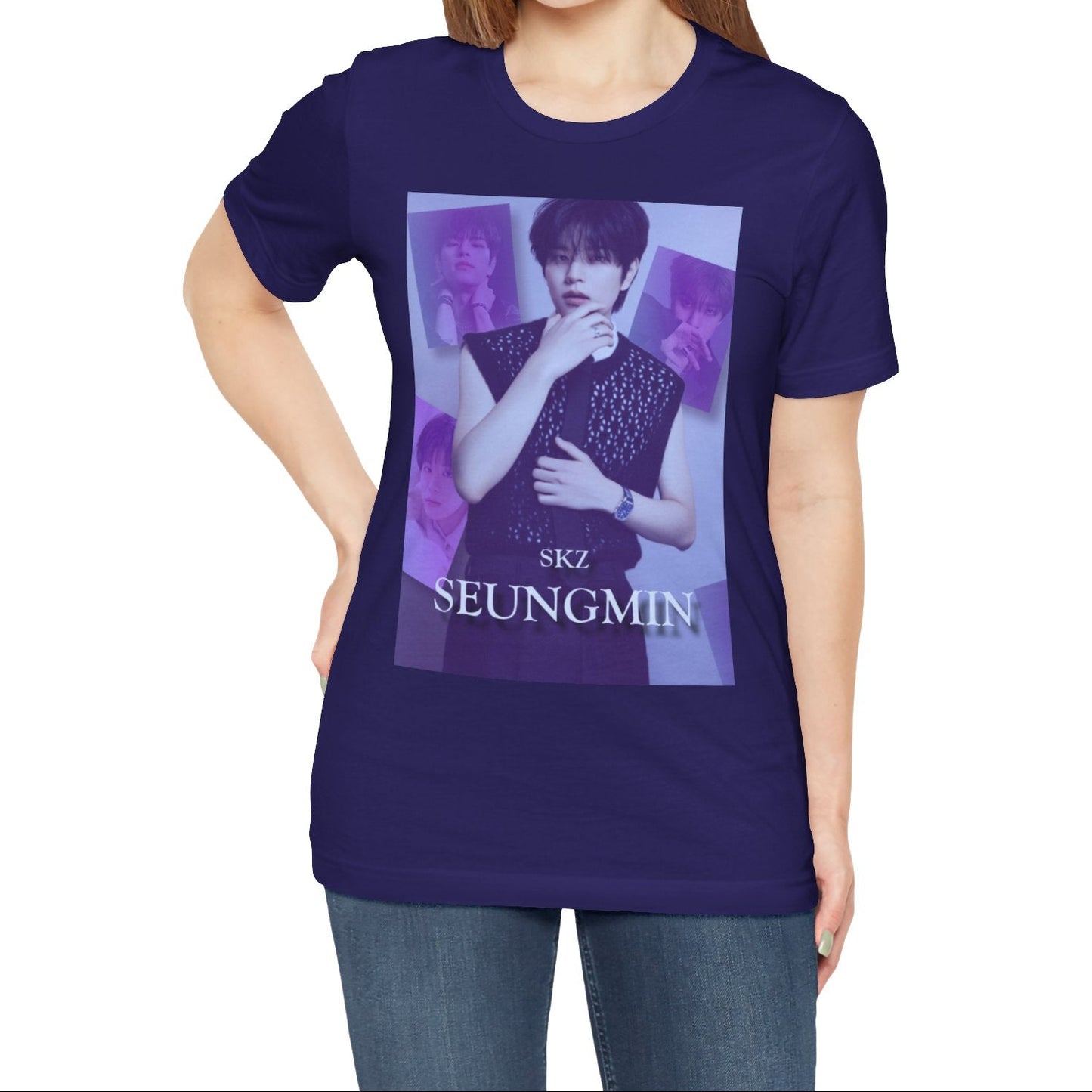 Female model showcasing the unisex, jersey, airlume combed and ringspun cotton T-Shirt in team navy, with a graphic design. It features Stray Kids' Seungmin in a sleeveless crochet top and blueberry tie. He poses thoughtfully against a periwinkle backdrop with a mist-covered collage of lavender, magazine-style photos. At the bottom, "SKZ SEUNGMIN" is written in pale lily-blue with a soft drop shadow. From ModeK Vetments.