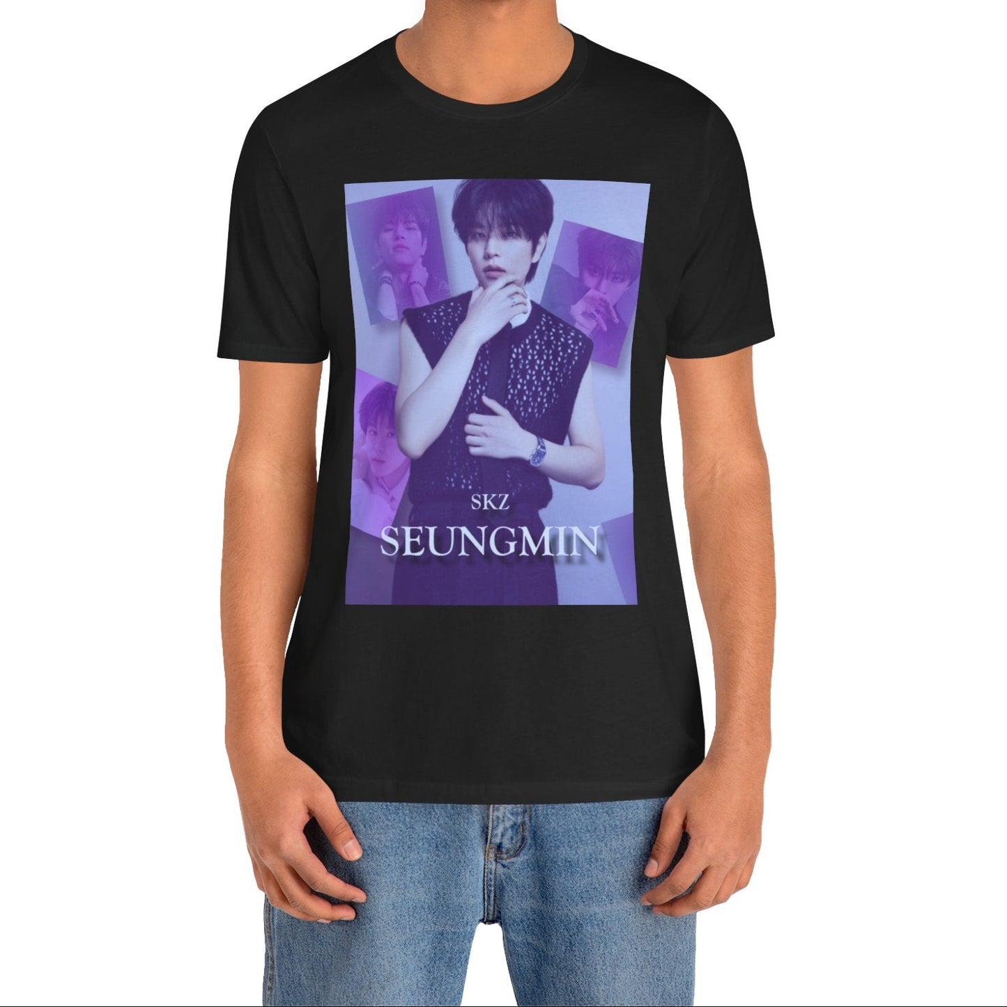 Male model showcasing the unisex, jersey, airlume combed and ringspun cotton T-Shirt in black, with a graphic design. It features Stray Kids' Seungmin in a sleeveless crochet top and blueberry tie. He poses thoughtfully against a periwinkle backdrop with a mist-covered collage of lavender, magazine-style photos. At the bottom, "SKZ SEUNGMIN" is written in pale lily-blue with a soft drop shadow. From ModeK Vetments.