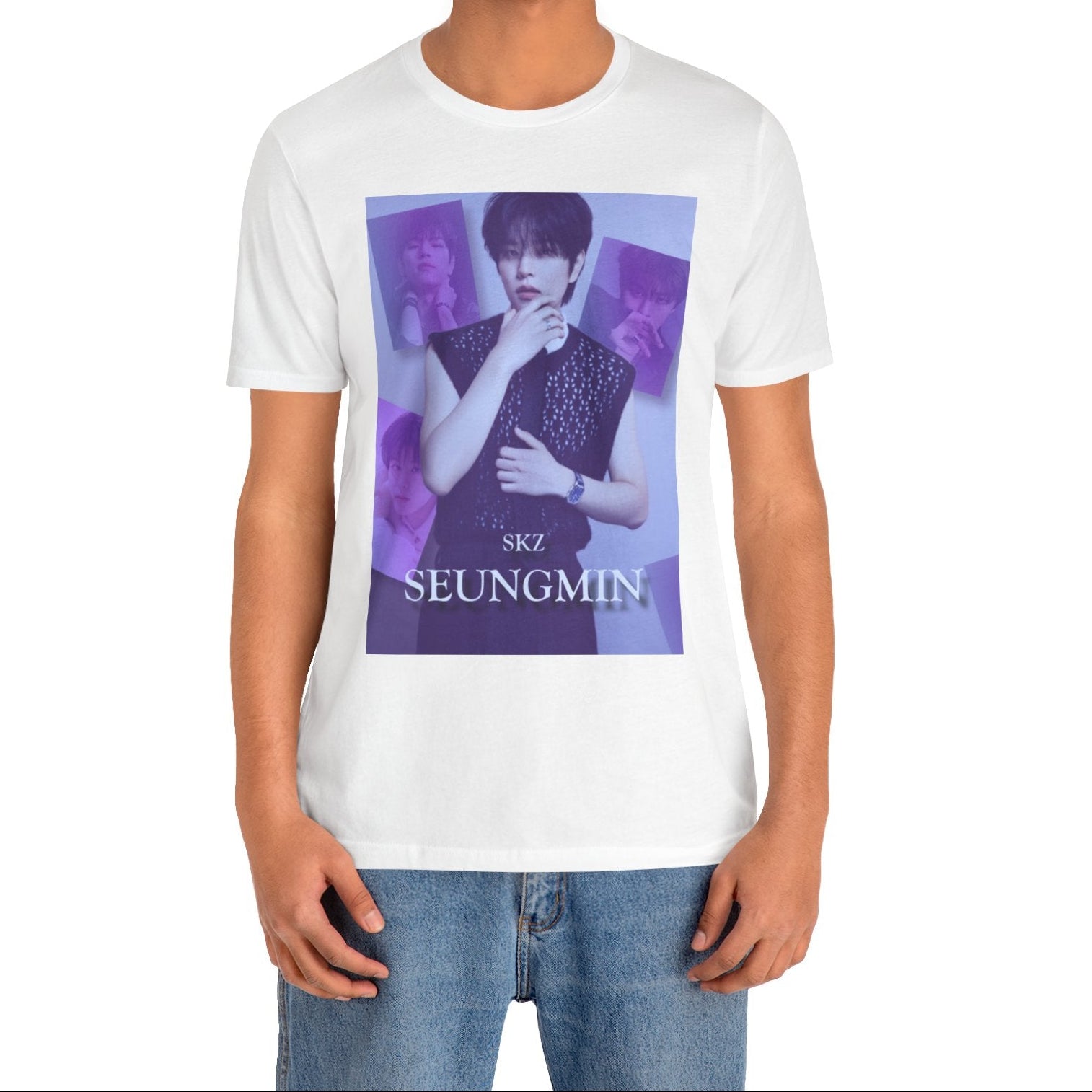 Male model showcasing the unisex, jersey, airlume combed and ringspun cotton T-Shirt in white, with a graphic design. It features Stray Kids' Seungmin in a sleeveless crochet top and blueberry tie. He poses thoughtfully against a periwinkle backdrop with a mist-covered collage of lavender, magazine-style photos. At the bottom, "SKZ SEUNGMIN" is written in pale lily-blue with a soft drop shadow. From ModeK Vetments.