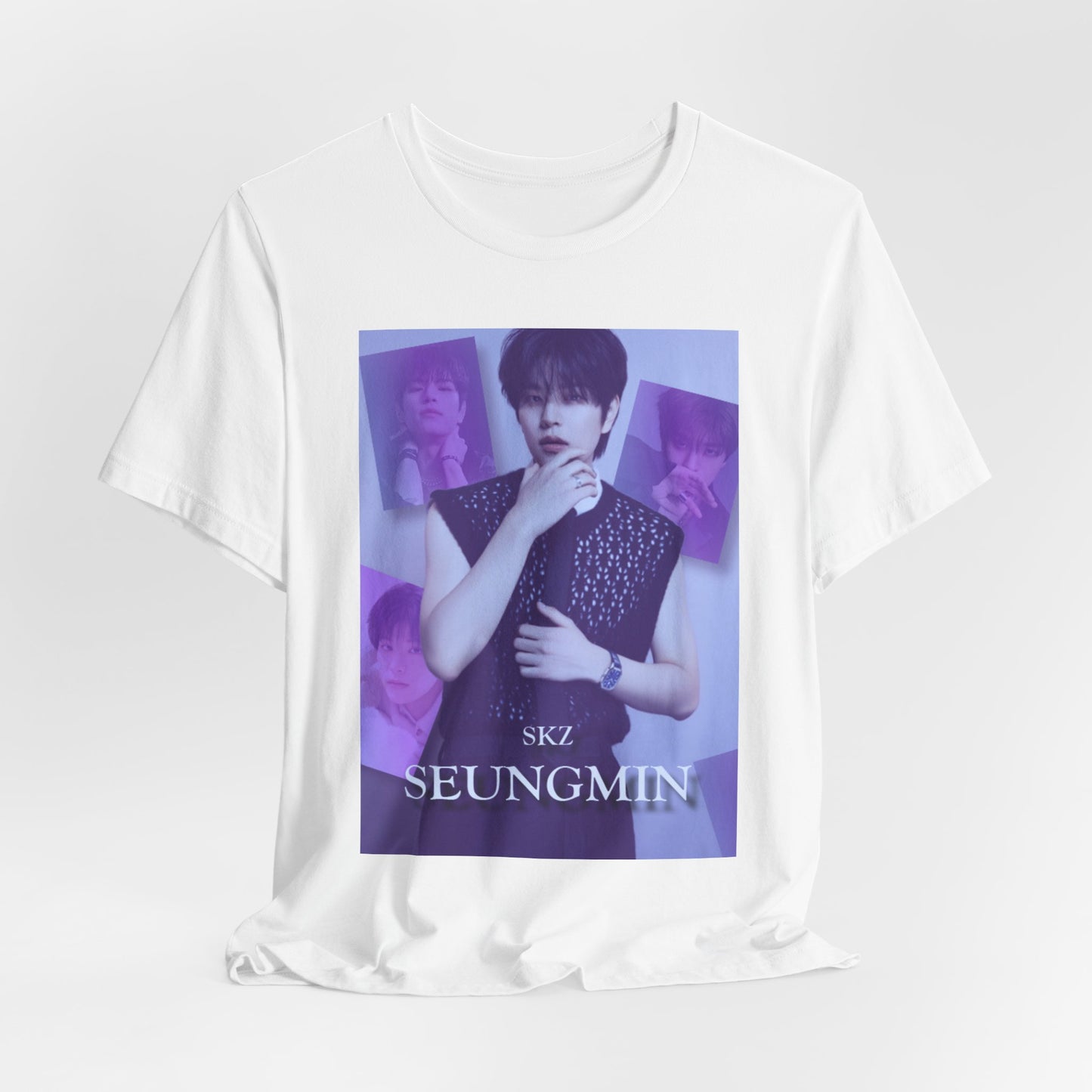 Draped unisex, jersey, airlume combed and ringspun cotton T-Shirt in white, with a graphic design. It features Stray Kids' Seungmin in a sleeveless crochet top and blueberry tie. He poses thoughtfully against a periwinkle backdrop with a mist-covered collage of lavender, magazine-style photos. At the bottom, "SKZ SEUNGMIN" is written in pale lily-blue with a soft drop shadow. From ModeK Vetments.