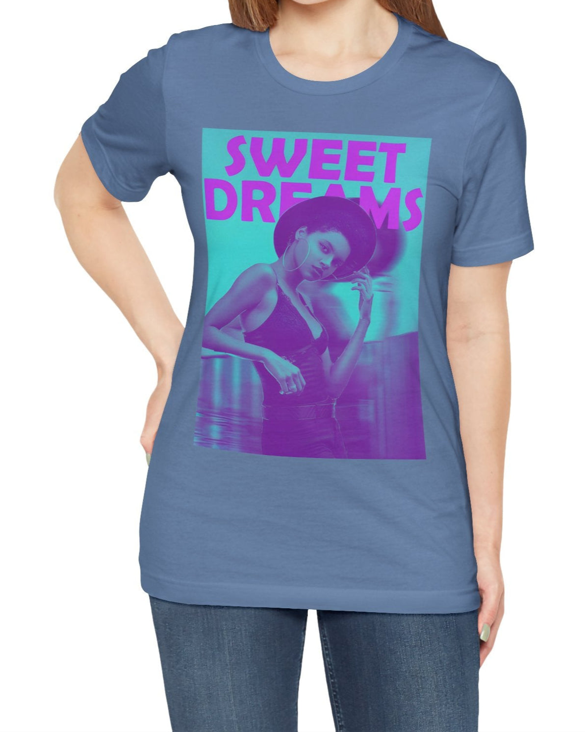 Unisex airlume cotton t-shirt in lavender blue, featuring a woman in a wide-brimmed hat appearing clearly over a blurred motion version of herself, as if caught between dream and sleep. The lilac-pink words “SWEET DREAMS” float above on a medium turquoise background, evoking the gentle melancholy of May evenings. From ModeK Vetements.