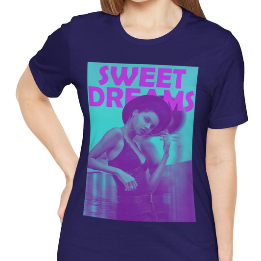 Unisex airlume cotton t-shirt in team navy, featuring a woman in a wide-brimmed hat appearing clearly over a blurred motion version of herself, as if caught between dream and sleep. The lilac-pink words “SWEET DREAMS” float above on a medium turquoise background, evoking the gentle melancholy of May evenings. From ModeK Vetements.