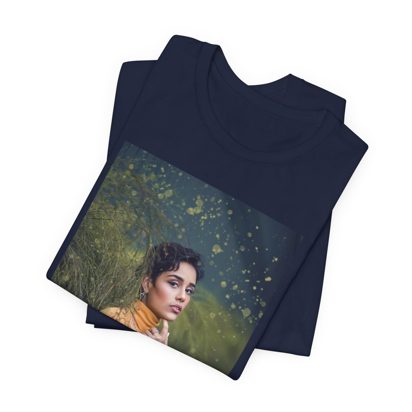 Folded unisex 100% airlume combed and ring-spun cotton t-shirt in navy featuring a woman in a yellow turtleneck. The image is layered with golden paint splashes creating a sense of motion and "Artistic Talent" where the subject looks real enough to step out of the picture. From ModeK Vetements.