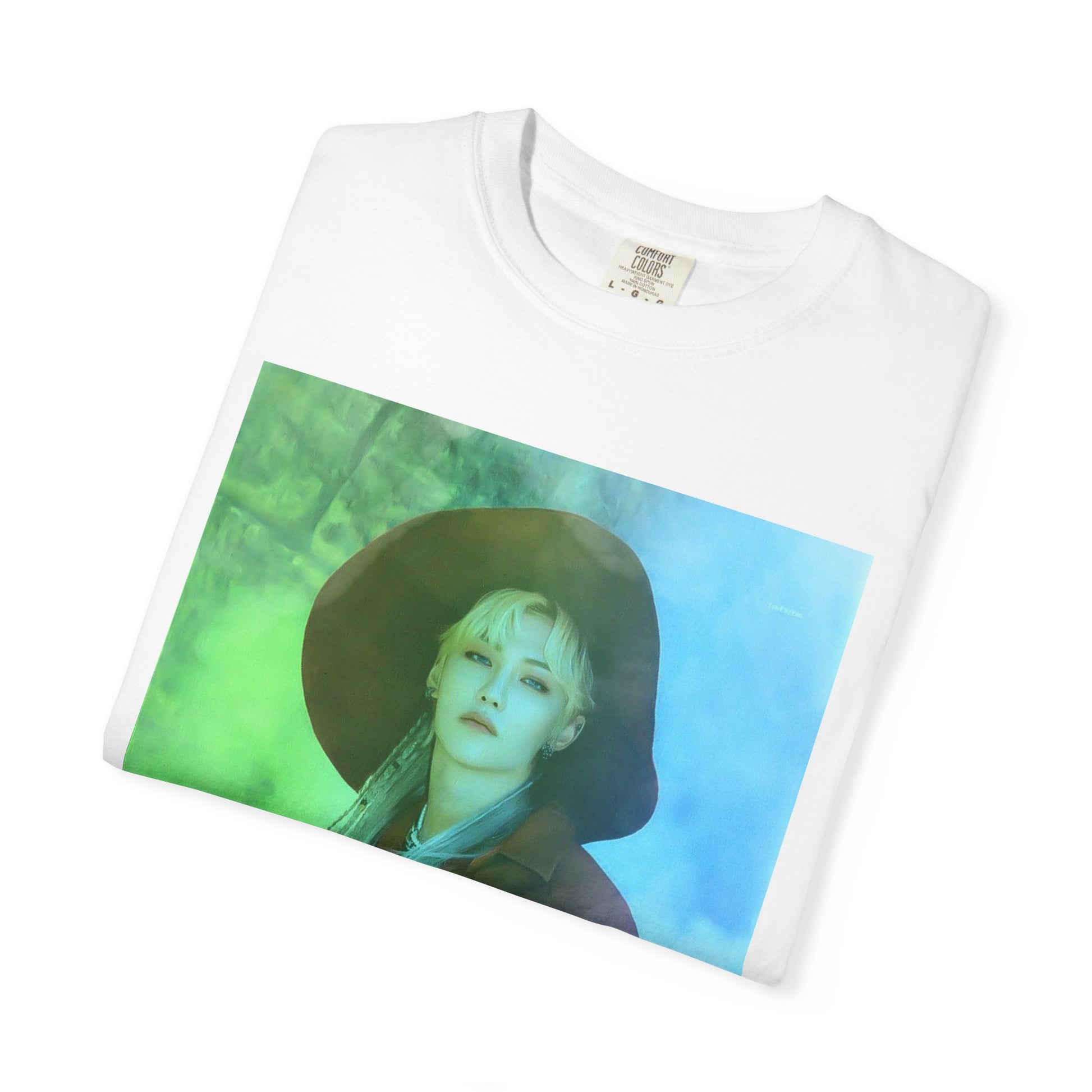 Folded Unisex 100% ring-spun cotton T-Shirt in white, featuring a portrait of Stray Kids' Felix wearing a large hat. It is as if he was painted on canvas with the effect of a mist, blending soft light blue and light green tones. From ModeK Vetements.